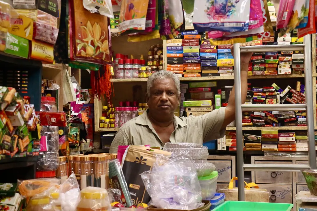 A shop owner at the counter of his grocery store